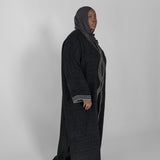 Person wearing a long black abaya with a hijab on a white background