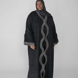 Woman wearing a black abaya with white embroidery on a white background