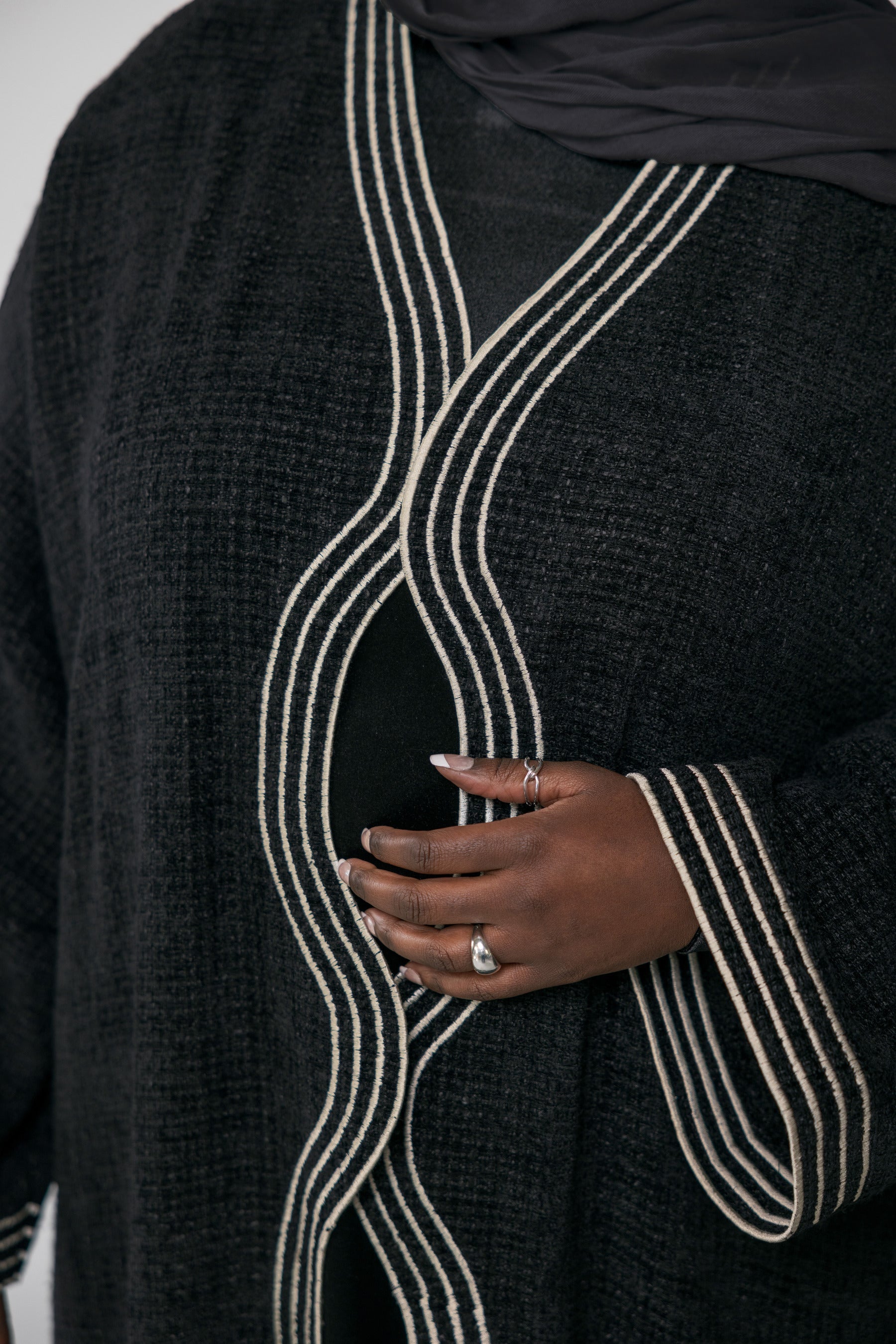 Black abaya with white embroidery trim on a plain background