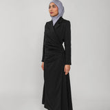 Woman wearing a black ruched abaya and gray hijab on a white background
