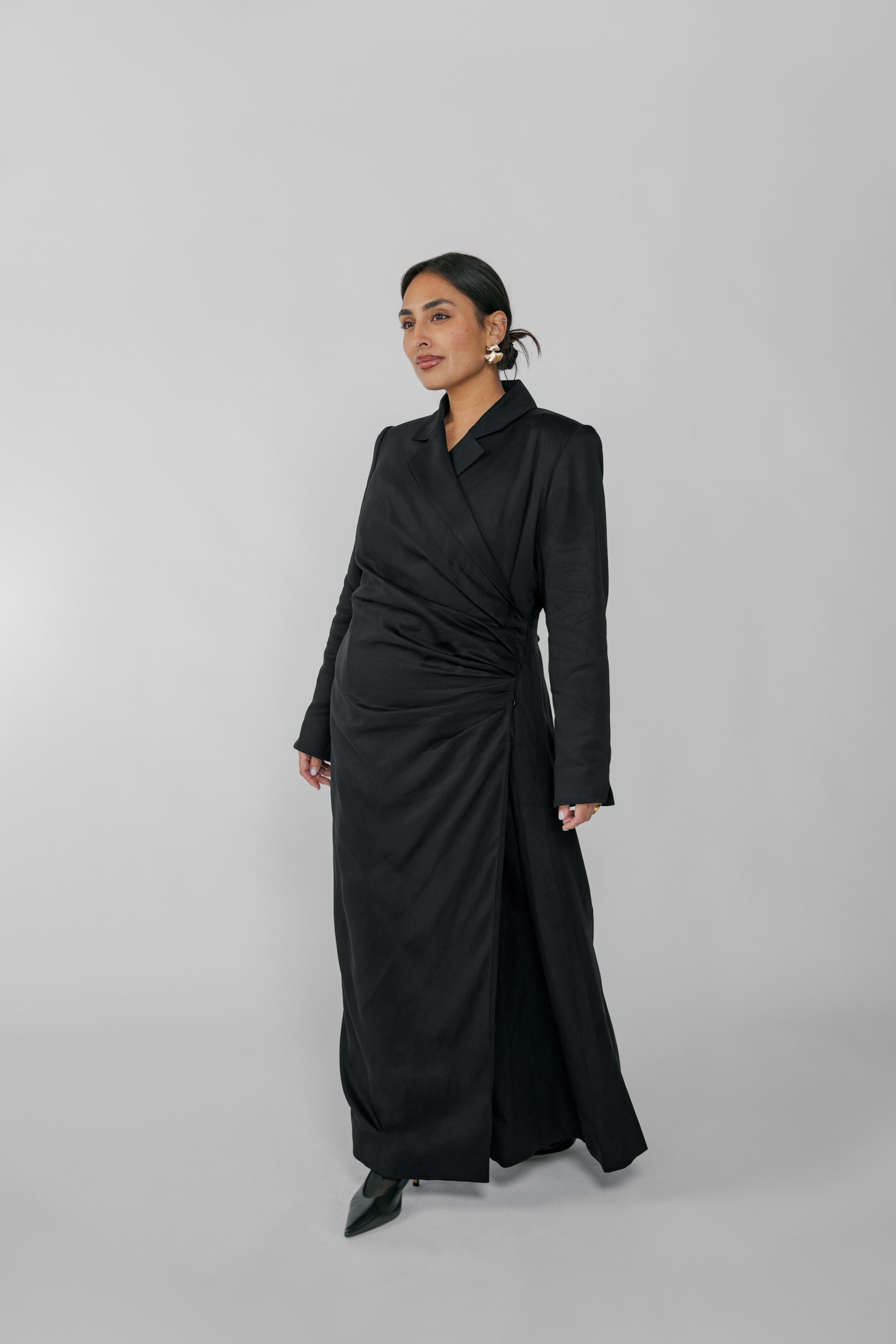 Woman wearing a black ruched abaya on a gray background