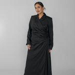 Woman wearing a black ruched dress against a gray background