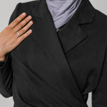 Person wearing a black ruched abaya and light gray hijab on a plain background