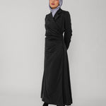 Woman wearing a black wrap abaya and gray hijab on a white background