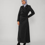 Woman wearing a black ruched abaya and gray hijab on a white background