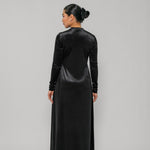 Woman wearing a black long-sleeve dress against a gray background