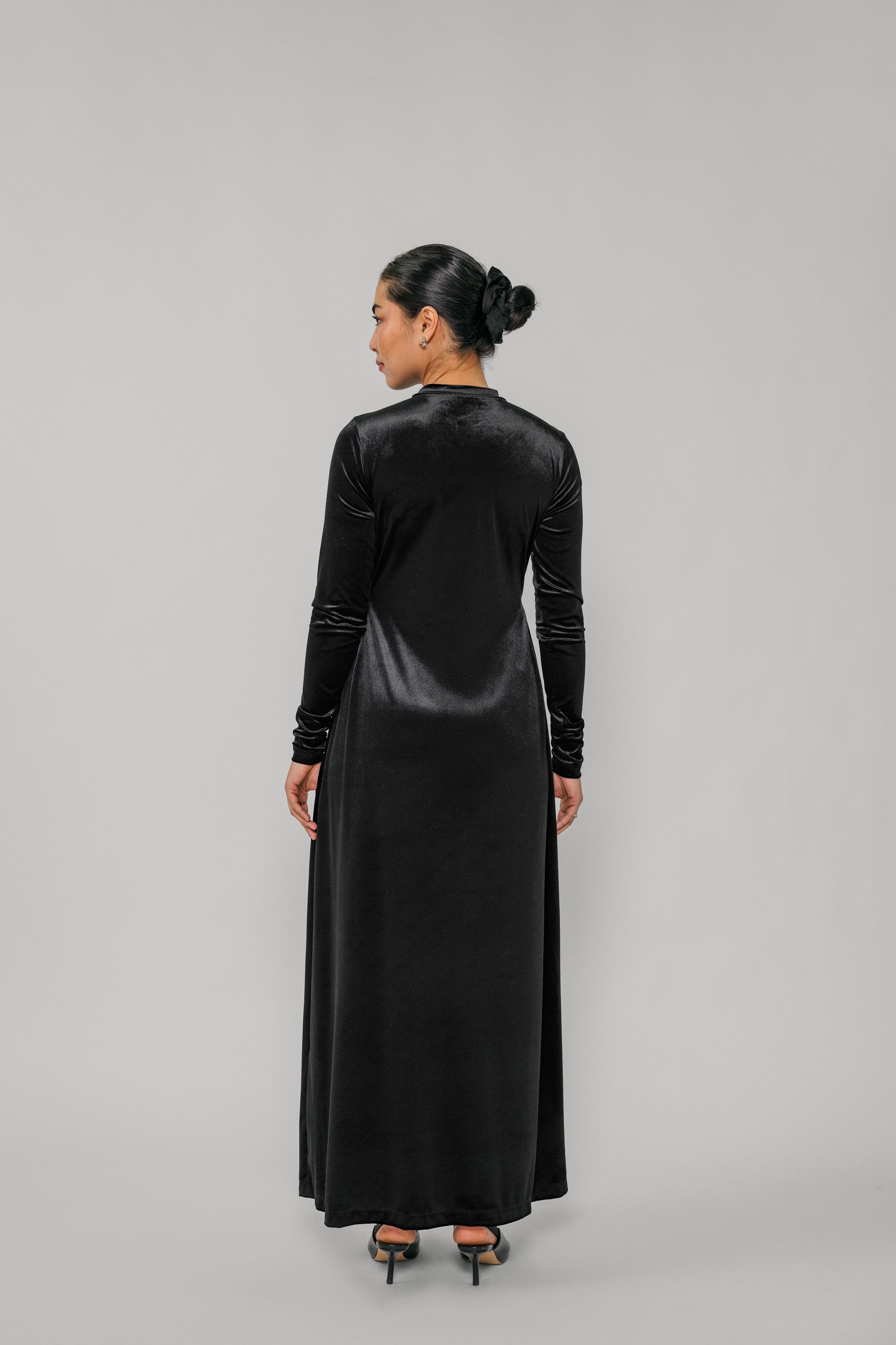 Woman wearing a black long-sleeve dress against a gray background