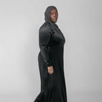 Woman wearing a black long-sleeve dress against a gray background