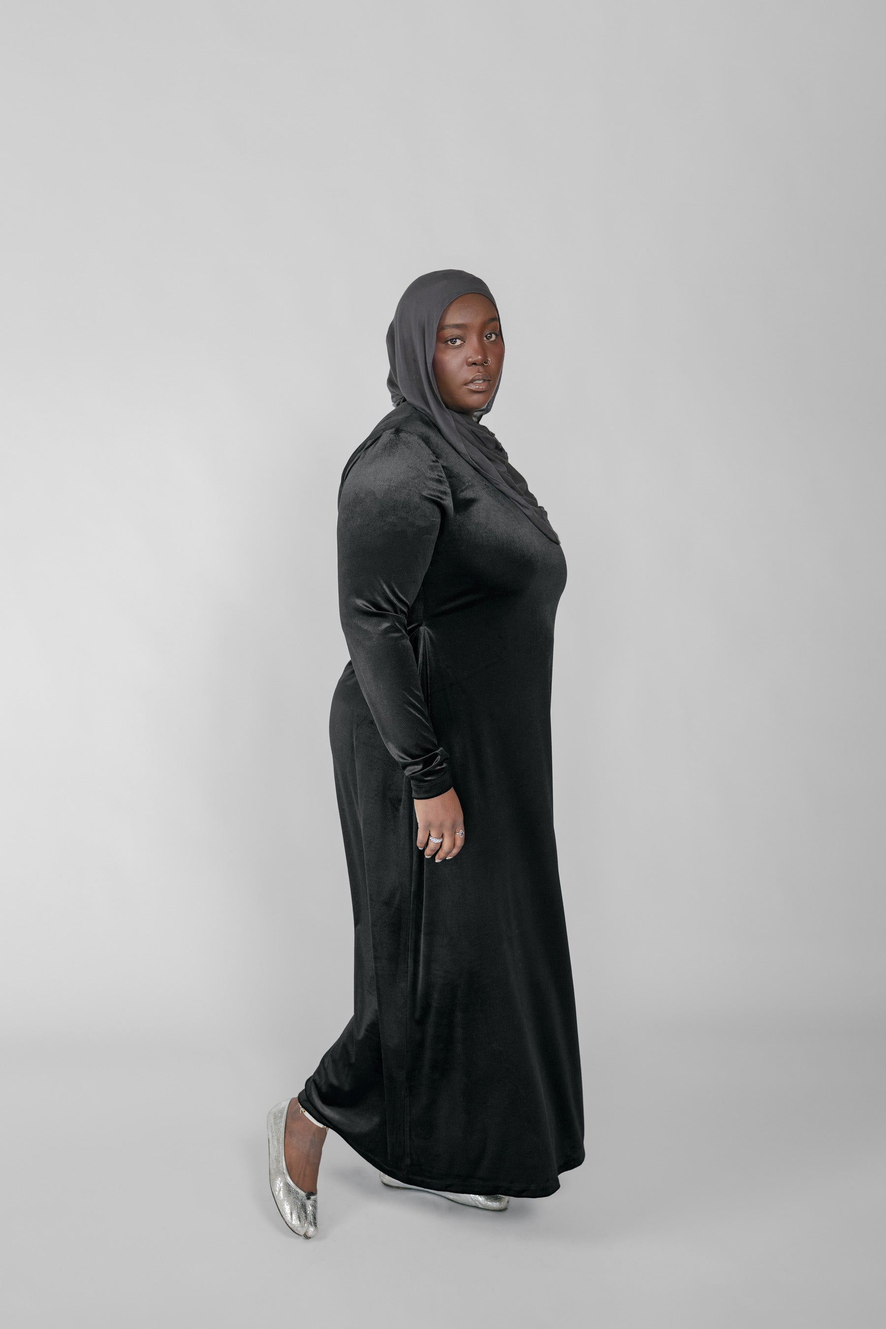 Woman wearing a black long-sleeve dress against a gray background