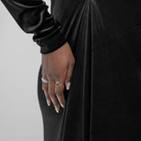 Woman wearing a black long-sleeve dress against a gray background