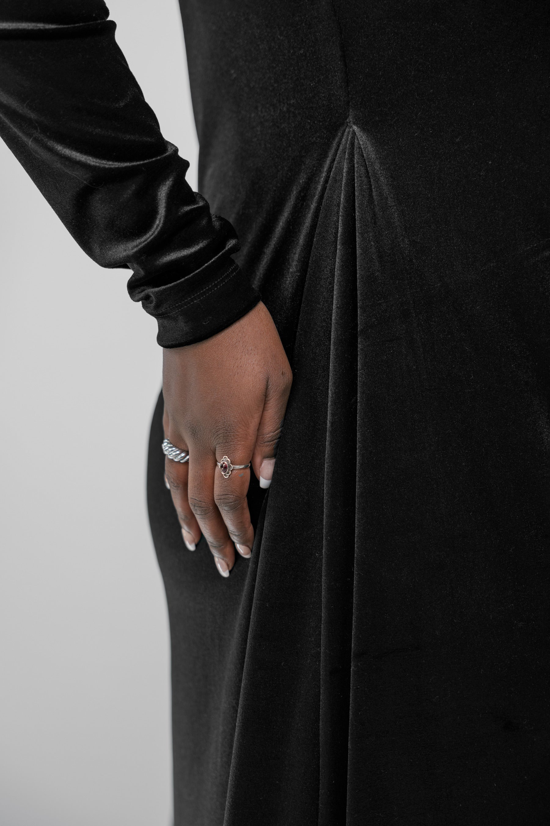 Woman wearing a black long-sleeve dress against a gray background