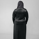 Person wearing a black abaya with a hijab on a light gray background