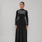 Woman wearing a black long-sleeve dress against a gray background