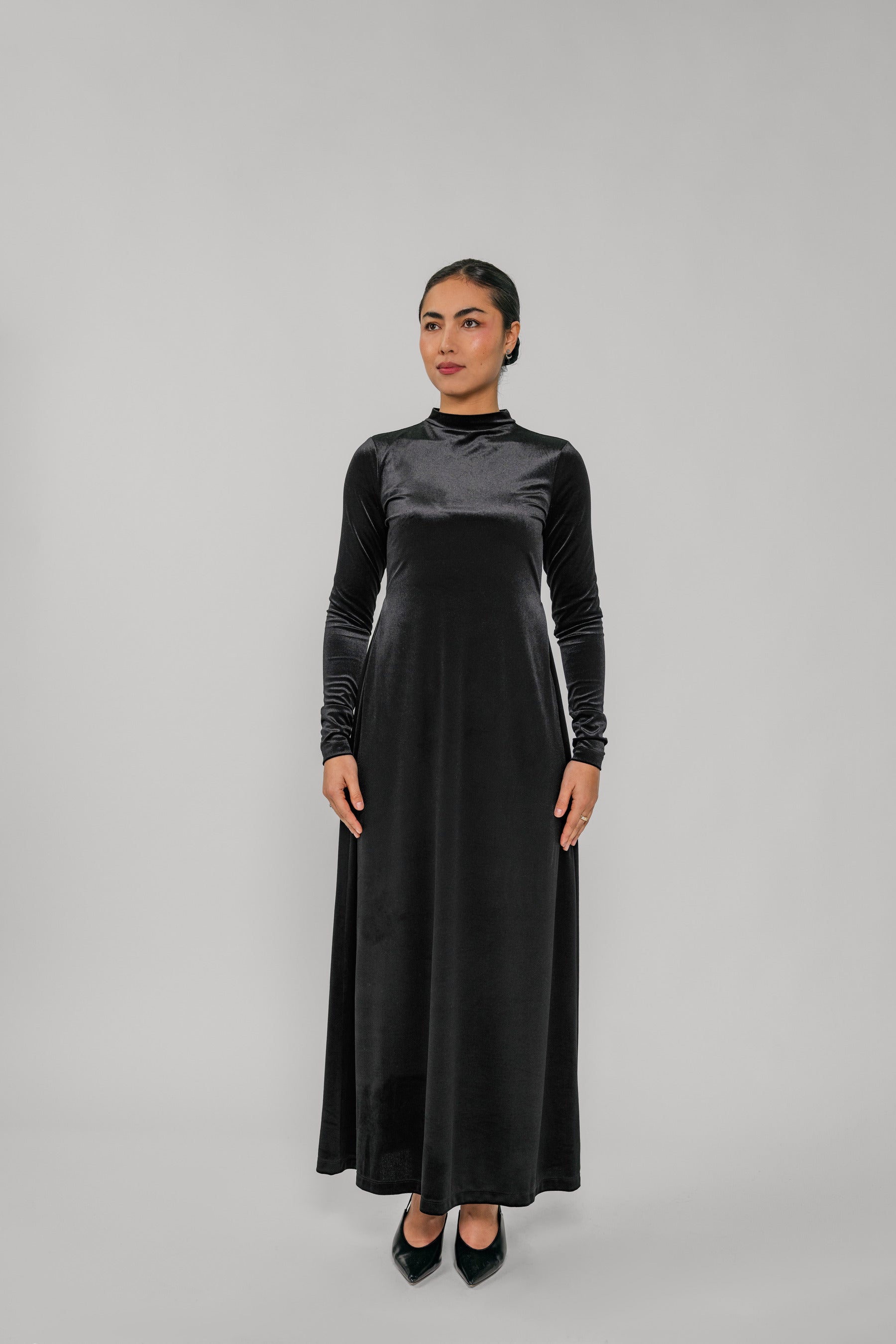 Woman wearing a black long-sleeve dress against a gray background