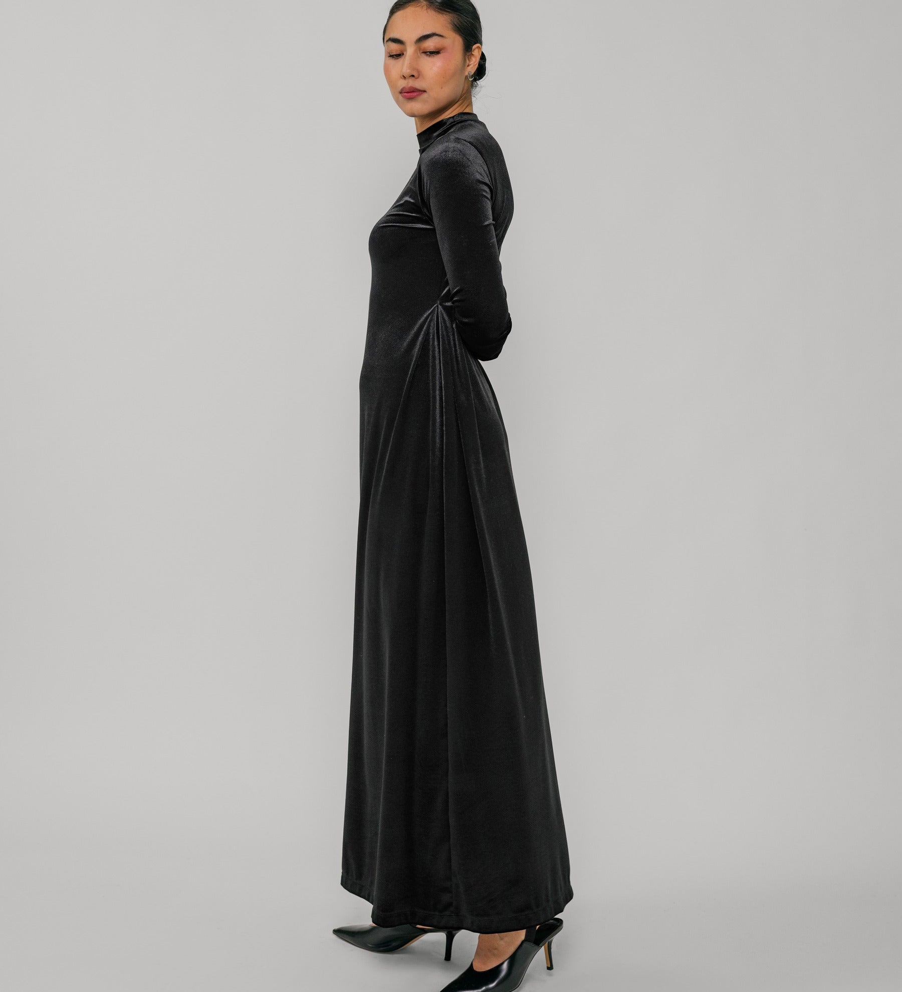 Woman wearing a black long-sleeve dress on a gray background