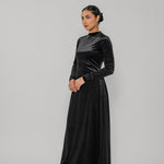 Woman wearing a black velvet dress against a gray background