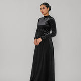 Woman wearing a black velvet dress against a gray background