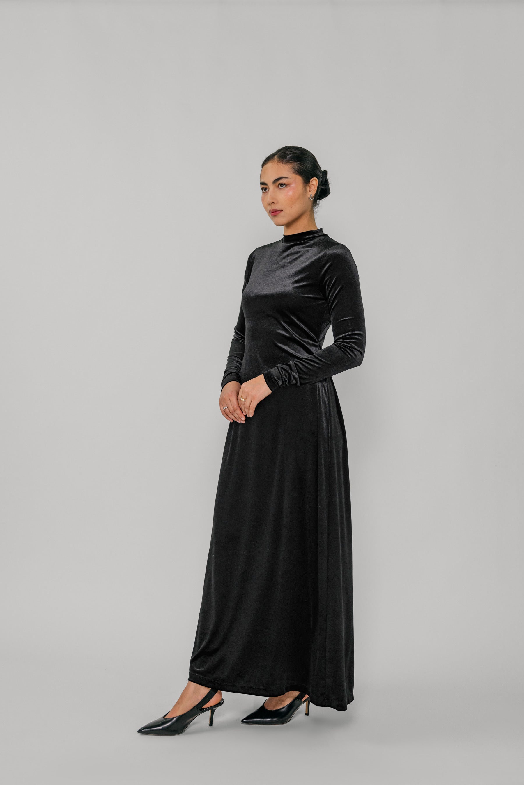 Woman wearing a black velvet dress against a gray background