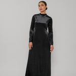 Woman wearing a black long-sleeve dress against a gray background