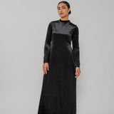 Woman wearing a black long-sleeve dress against a gray background