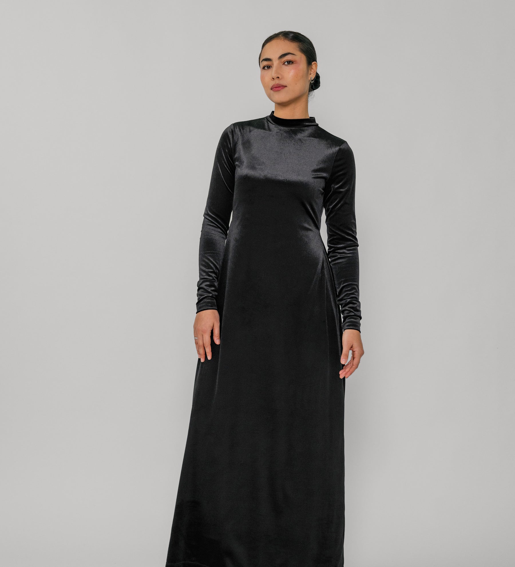 Woman wearing a black long-sleeve dress against a gray background