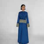 Woman wearing a blue dress with a patterned belt on a white background