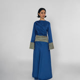 Woman wearing a blue dress with a patterned belt on a white background