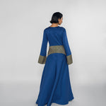 Woman wearing a blue dress with a striped patterned waistband on a white background