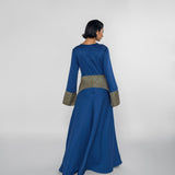 Woman wearing a blue dress with a striped patterned waistband on a white background