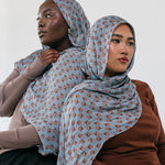 Two women wearing patterned hijabs against a white background