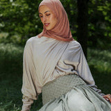 Woman in a hijab sitting on a tree stump in a natural setting