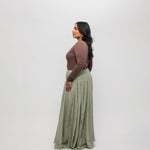 Woman wearing a brown-colored top, and green skirt on a white background
