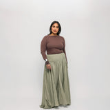 Woman wearing a brown-colored top, and green skirt on a white background