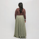 Woman wearing a brown-colored top, and green skirt on a white background