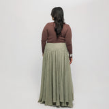 Woman wearing a brown-colored top, and green skirt on a white background