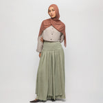 Woman wearing a hijab and long braided cascade skirt on a white background