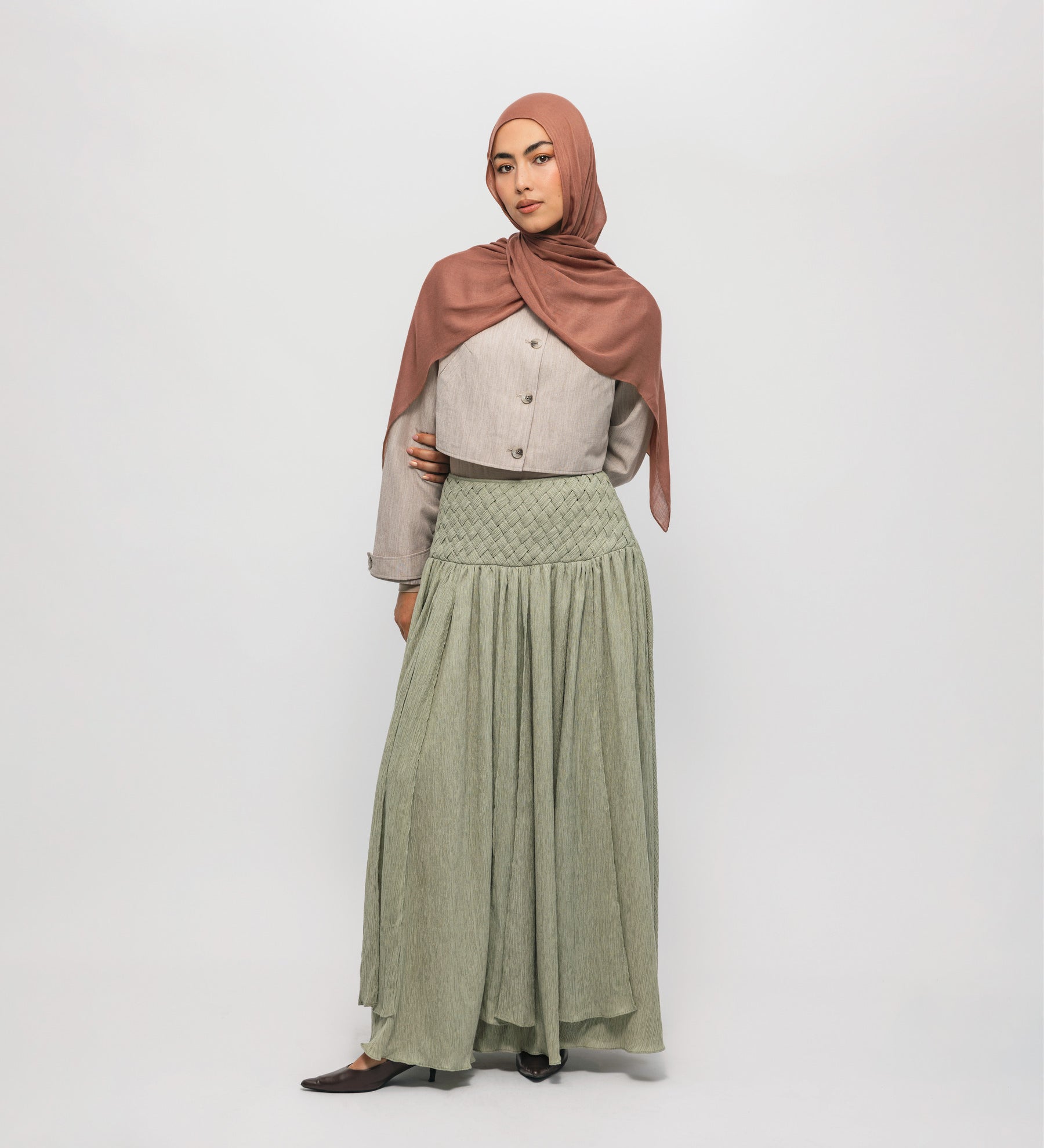 Woman wearing a hijab and long braided cascade skirt on a white background