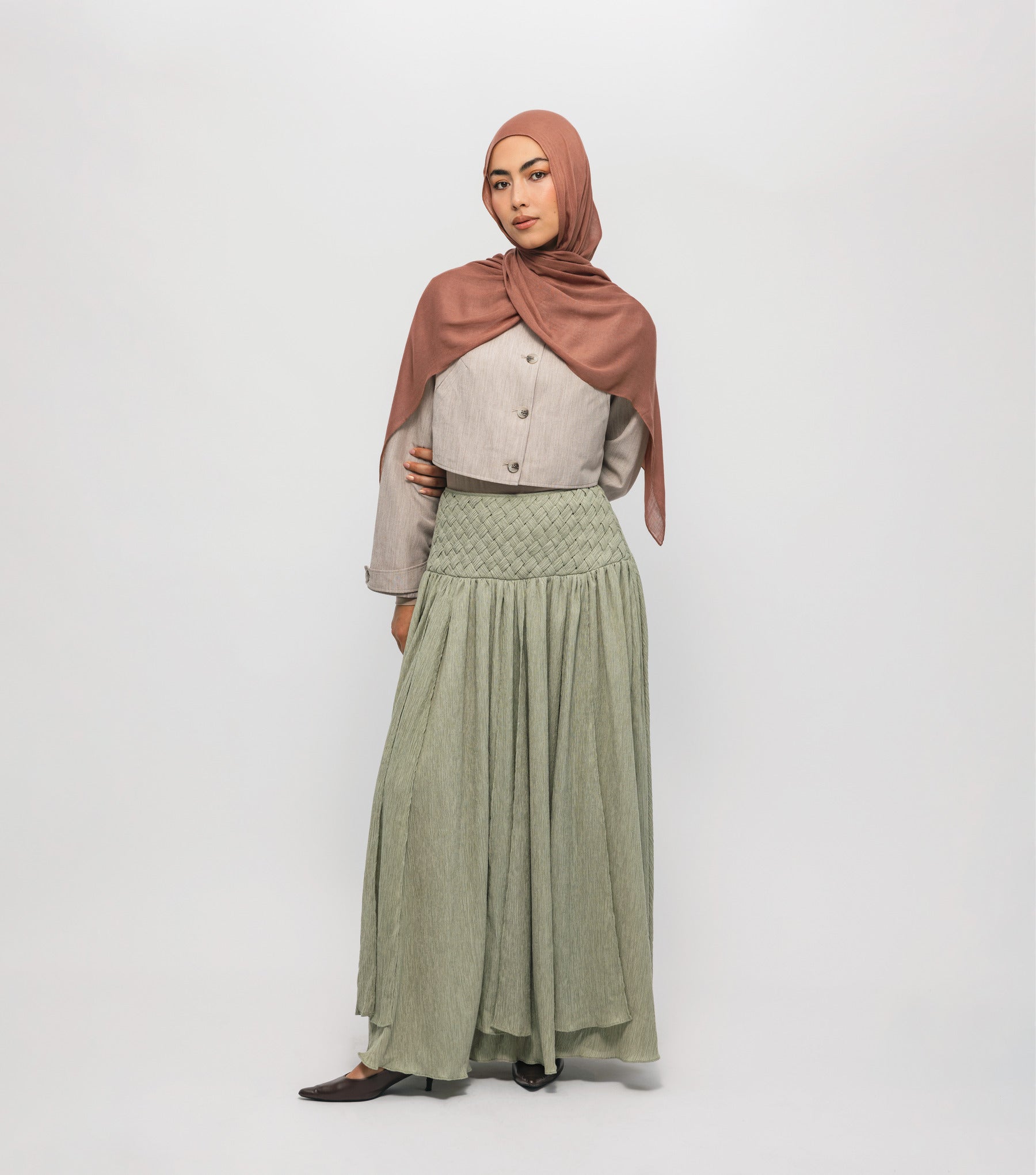Woman wearing a hijab and long braided cascade skirt on a white background