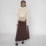 Woman wearing a cream top and brown skirt on a white background