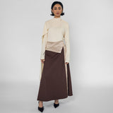 Woman wearing a cream top and brown skirt on a white background