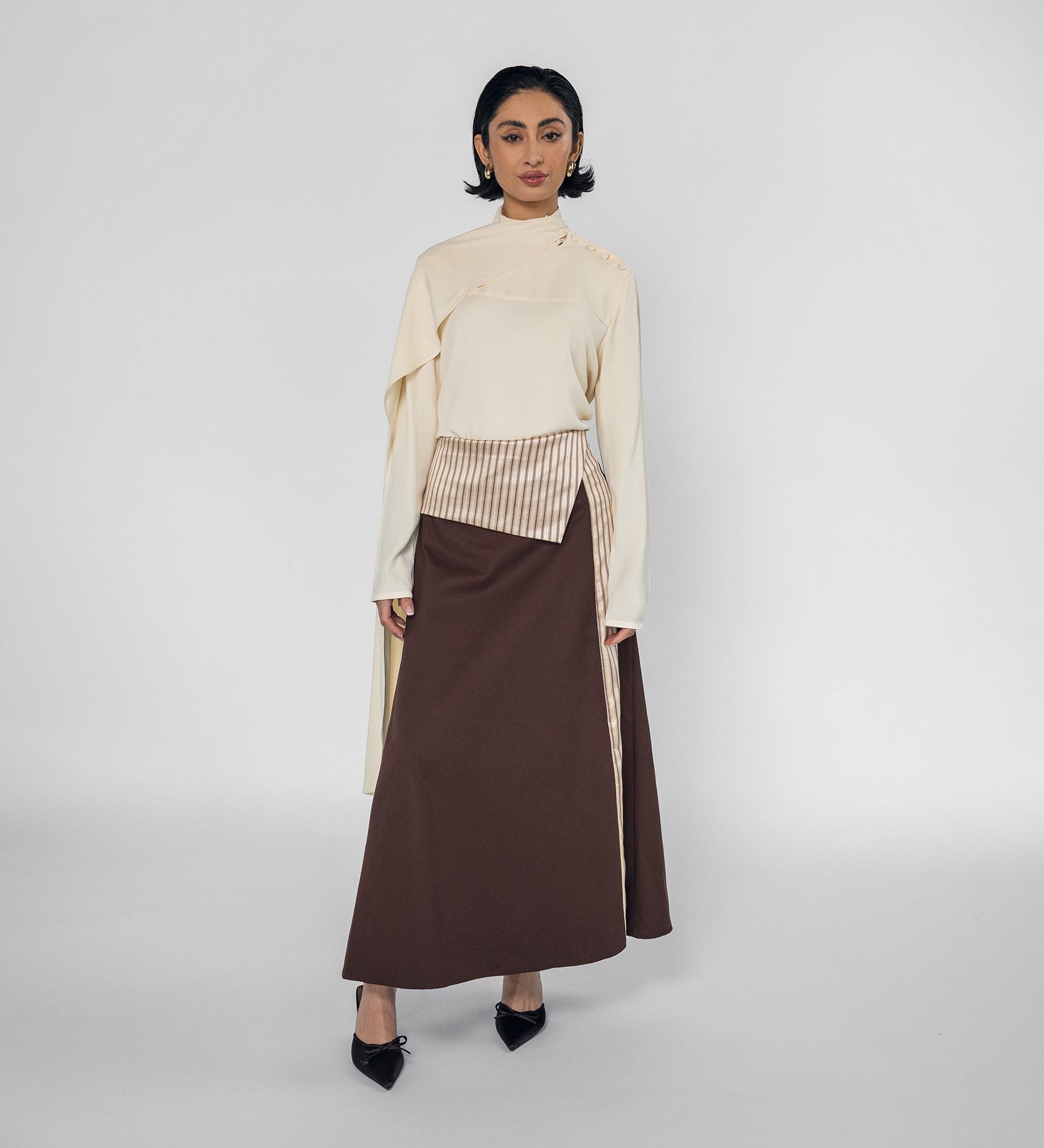 Woman wearing a cream top and brown skirt on a white background