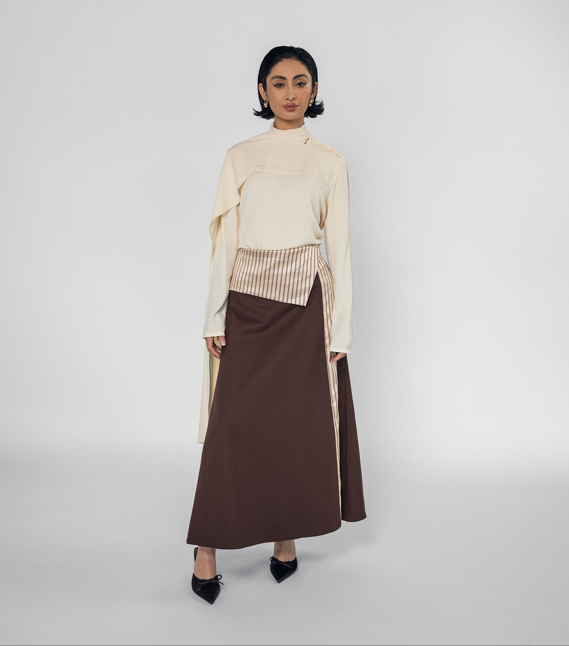 Woman wearing a cream top and brown skirt on a white background