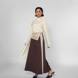 Woman wearing a cream blouse and brown skirt with a white background