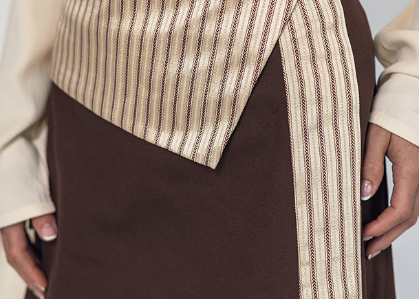 Brown skirt with a striped belt worn by a person against a neutral background