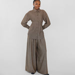 Person wearing a brown outfit with wide-leg pants on a white background