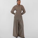 Person wearing a brown outfit with wide-leg pants on a white background