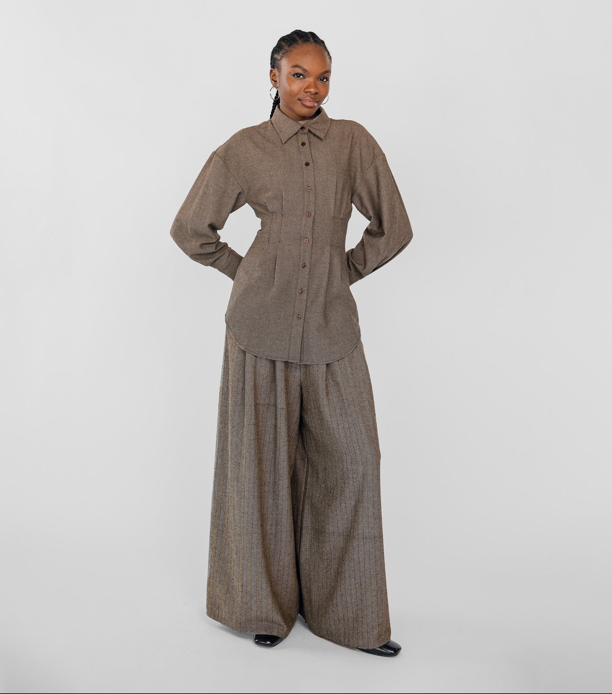 Person wearing a brown outfit with wide-leg pants on a white background