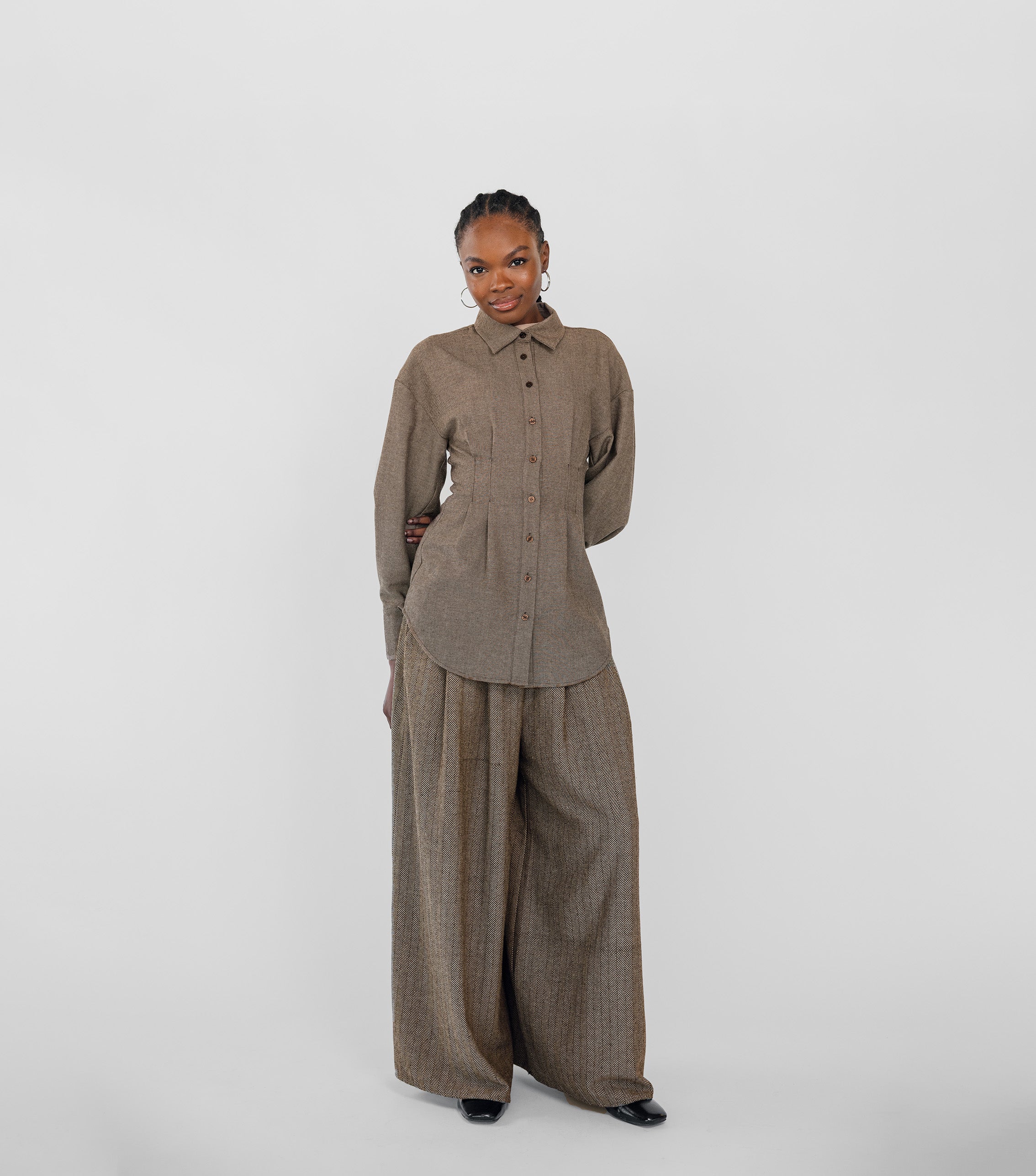 Person wearing a brown herringbone outfit on a white background