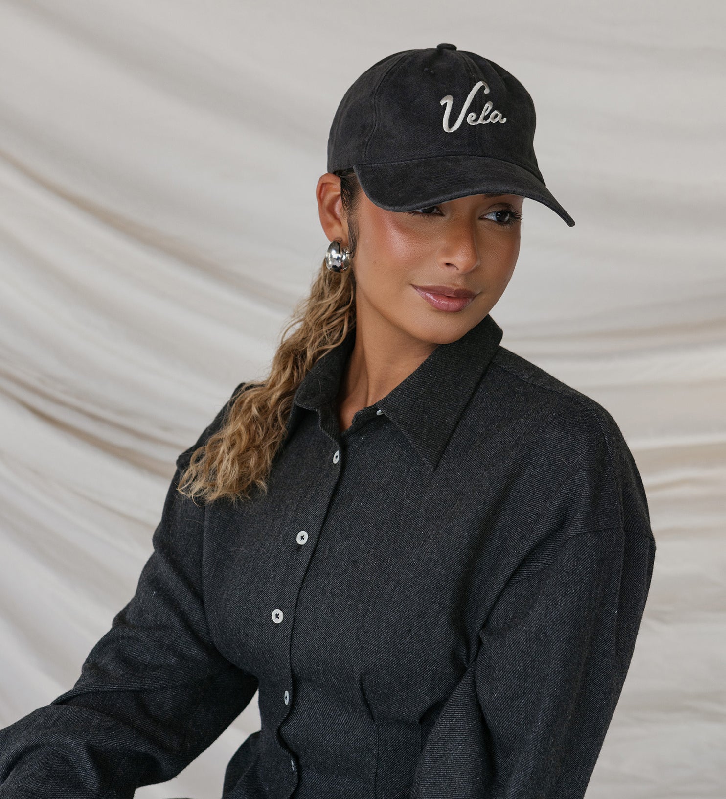 Person wearing a black cap with 'Vela' branding against a neutral background
