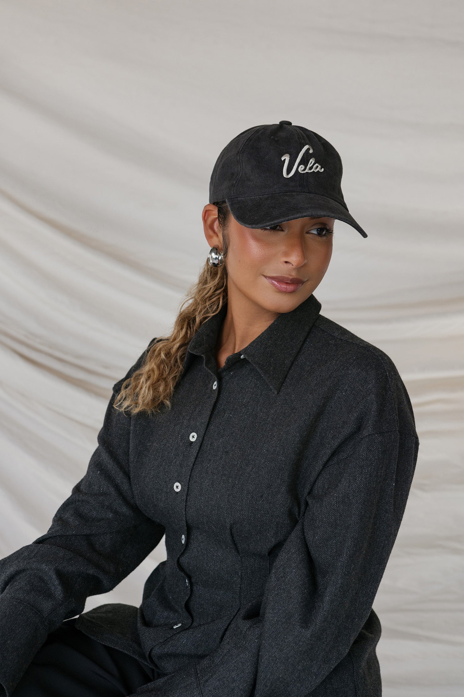 Person wearing a black cap with 'Vela' branding against a neutral background